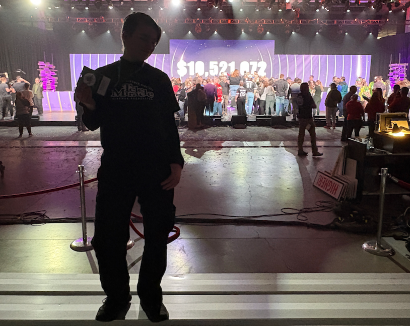 Mac standing in front of the Telemiracle 50 final in volunteer uniform.